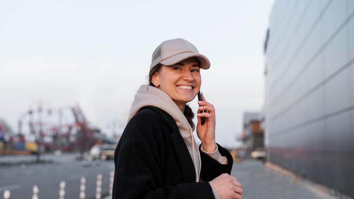A smiling person making an international call on a smartphone against a city backdrop.
